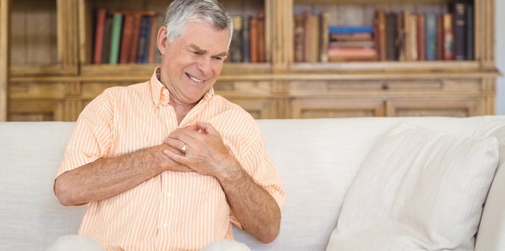 Senior man suffering from chest pain in living room at home