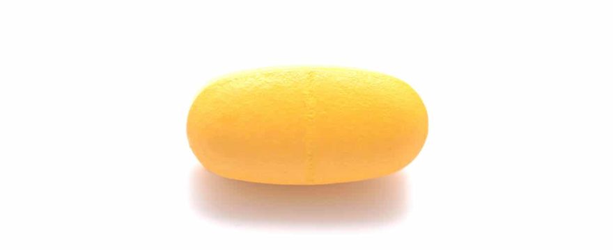 oval yellow pill on white background, no inscription