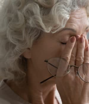 older female presses hands to eyes in pain